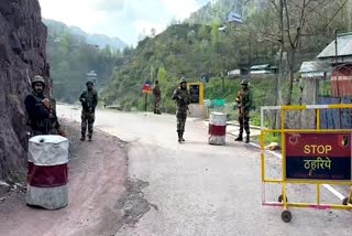 Indian Army and J and K Police personnel stand guard on a road after foiling an infiltration bid in Jammu and Kashmir