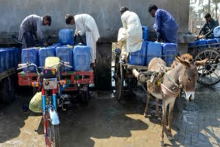 Vendors load cans of drinking water for sale on their motorcycle and donkey-drawn carts, as they fill them from a private water supply plant in Jacobabad in southern Sindh province on February 18, 2025.