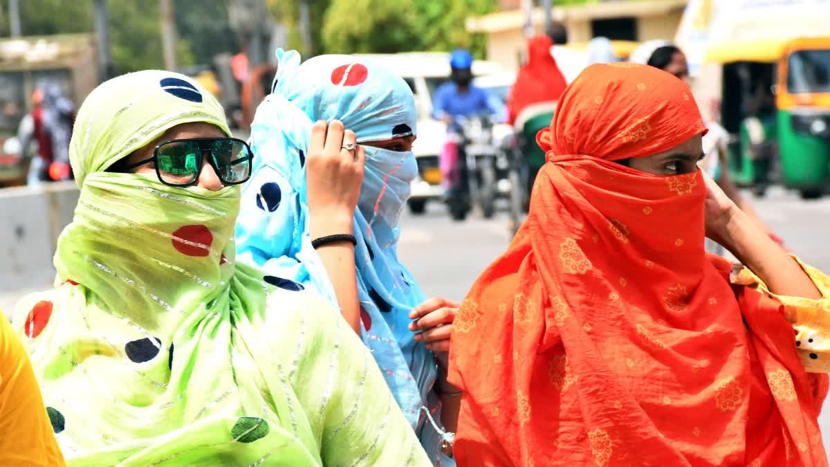 Women cover their faces to protect themselves from the scorching sun on a summer day in Kanpur.