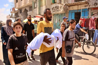 A Palestinian man carries a body during a funeral after an Israeli strike on a school housing displaced Palestinians in Gaza City's Zaytoun neighbourhood on September 21, 2024.