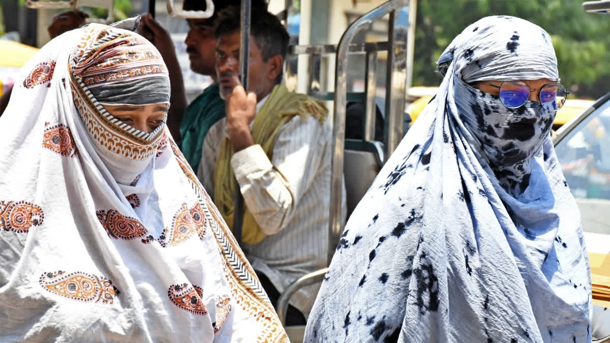 Women cover their faces with scarves to protect themselves from the scorching sun on a hot summer day.