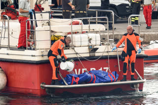 Italian firefighter divers bring ashore in a plastic bag the body of one of the victims of a shipwreck, in Porticello, Sicily, southern Italy on Thursday.