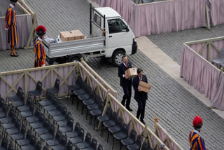 Two men carry boxes during the preparations in St. Peter's Square ahead of the arrival of the body of Pope Francis, who will lie in state at St. Peter's Basilica for three days, at the Vatican, Wednesday, April 23, 2025.