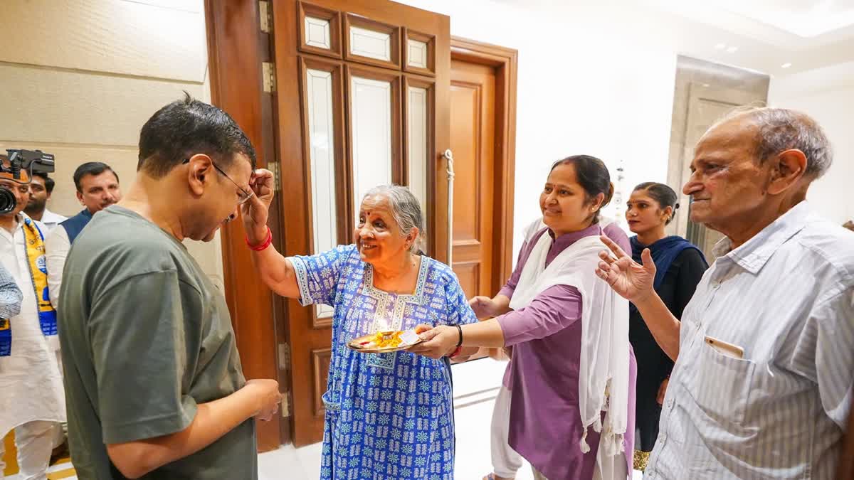 Arvind Kejriwal's mother (M) applies 'tilak' on his forehead while his father looks on