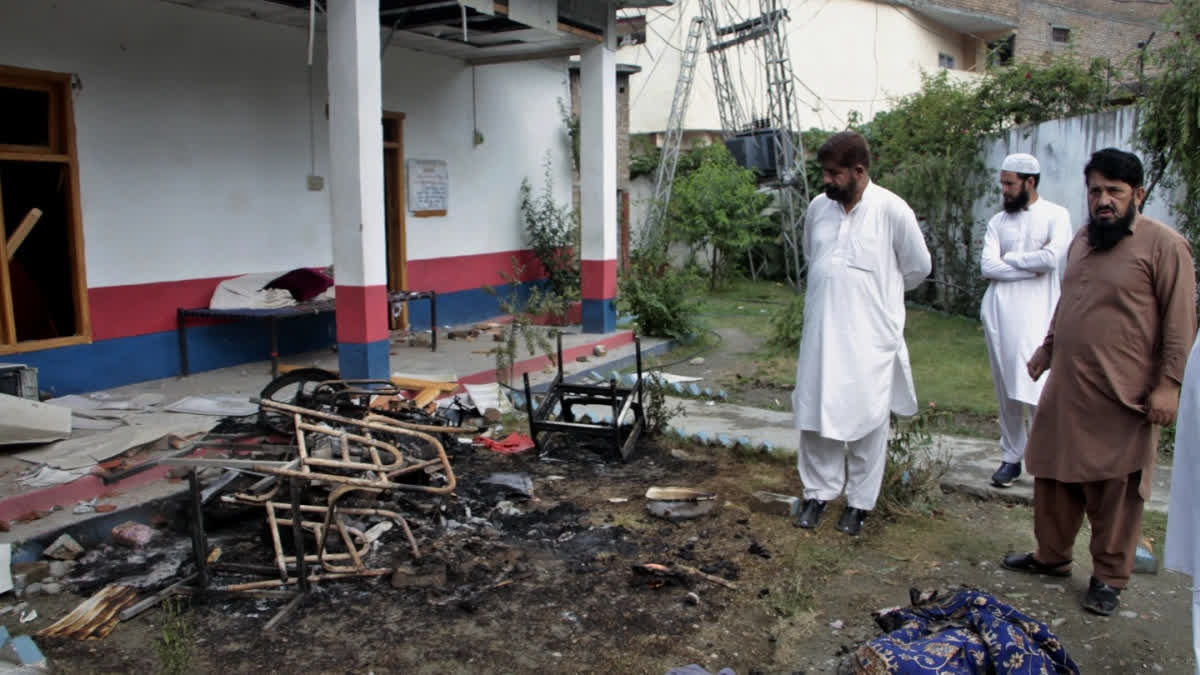 Policemen in plain clothes examine the burnt furniture torched by mob in Swat