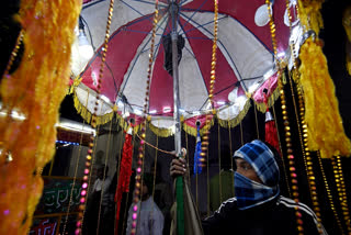 In this photograph taken on December 15, 2024, a brass band member holds an embellished umbrella with lights during a wedding procession in New Delhi.