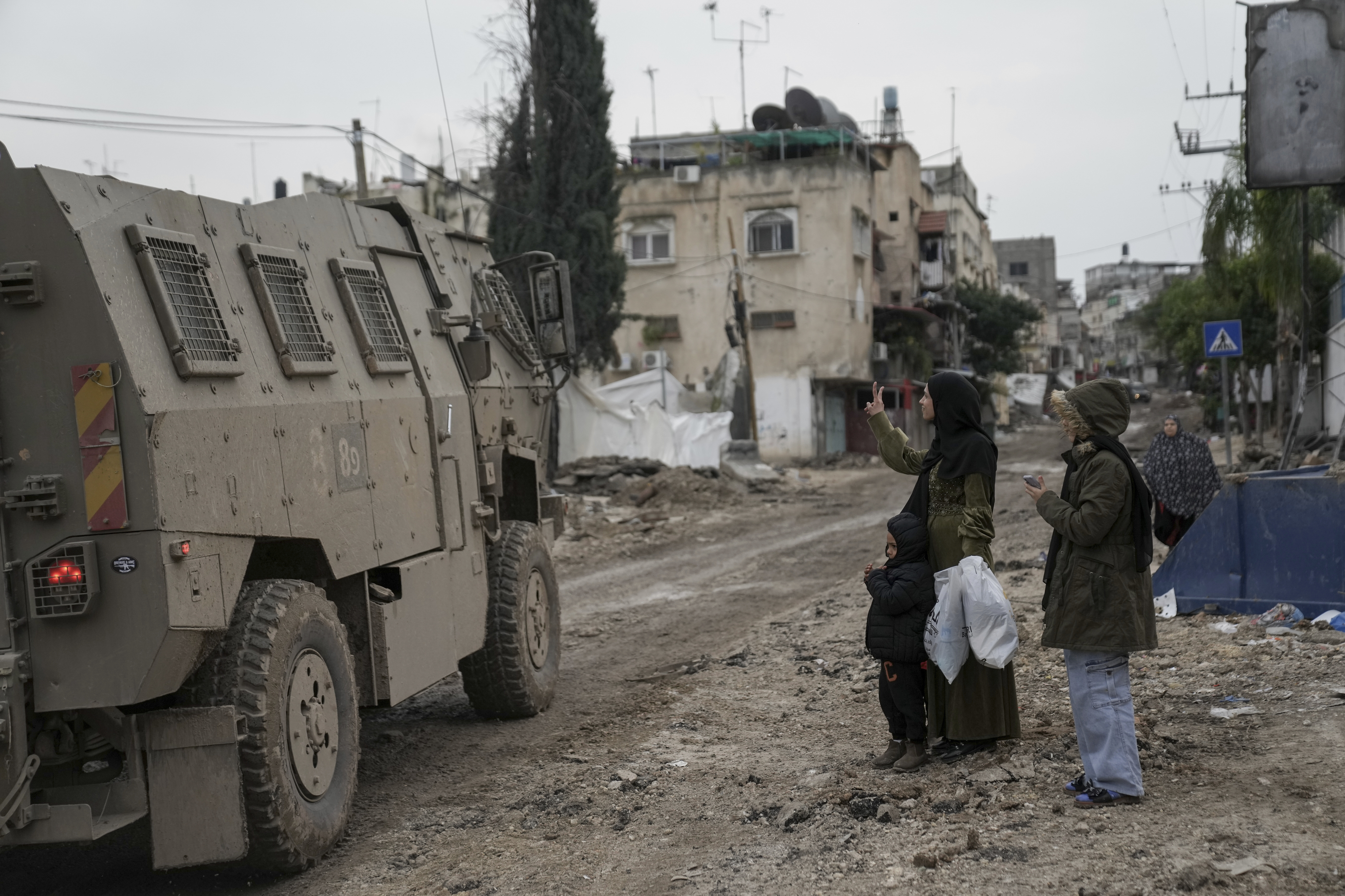 غزہ میں فلسطینی خاتون اسرائیلی فوج کو وکٹری یعنی جیت کا نشان بتاتے ہوئے۔(PHOTO: AP)