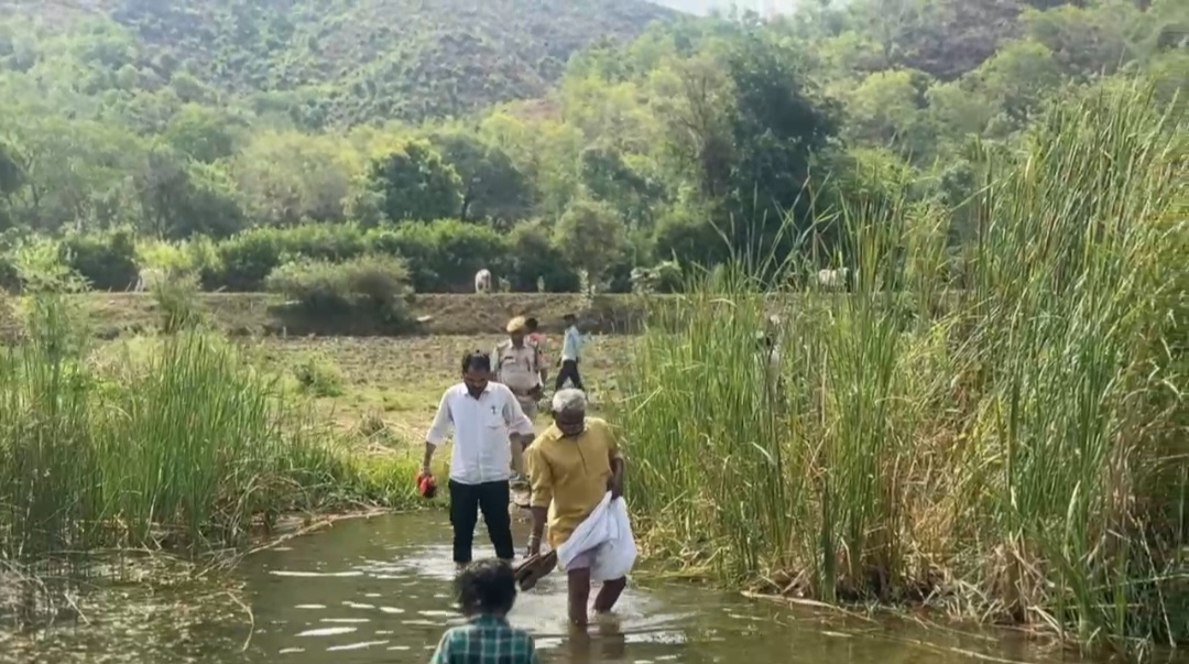 Rajasthan Minister Babulal Kharadi crossing a stream bare foot with shoes in his hand during his visit to a tribal area