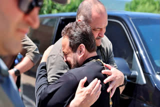 Head of Dagestan Republic Sergei Melikov, center, embraces and comforts a priest as he visits the Church in Derbent after a counter-terrorist operation.