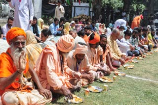 Saints from the Amarnath Yatra eat langar organized by the head priest of the Chhari Mubarak custodian Mahant Deependra Giri, in Pahalgam on Monday.