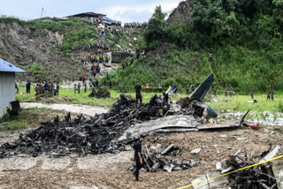 Rescuers and officials stand at the crash site after a Saurya Airlines' plane crashed during takeoff at the Tribhuvan International Airport in Kathmandu on July 24, 2024.