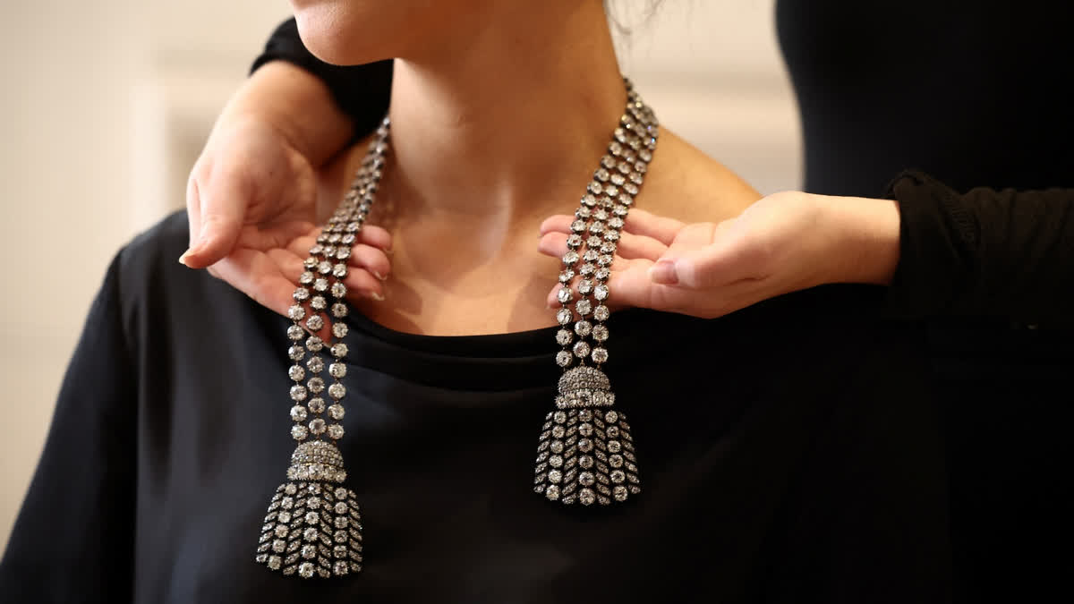 A gallery assistant poses wearing an 18th century diamond jewel necklace.