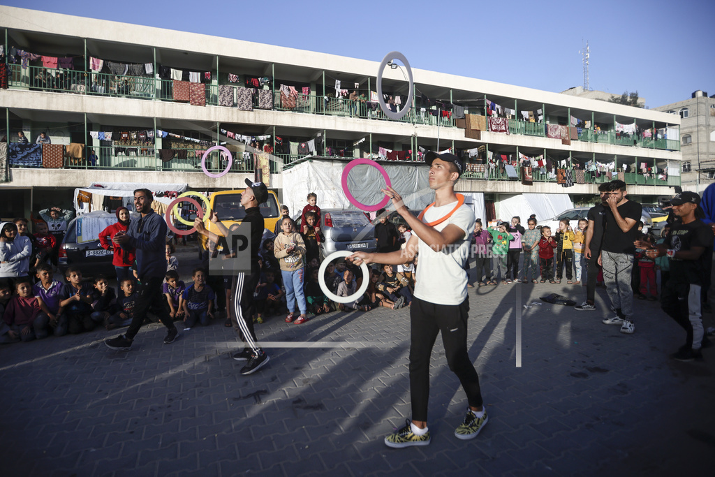 Palestinians present an entertainment performance for displaced children sheltering at a UN school