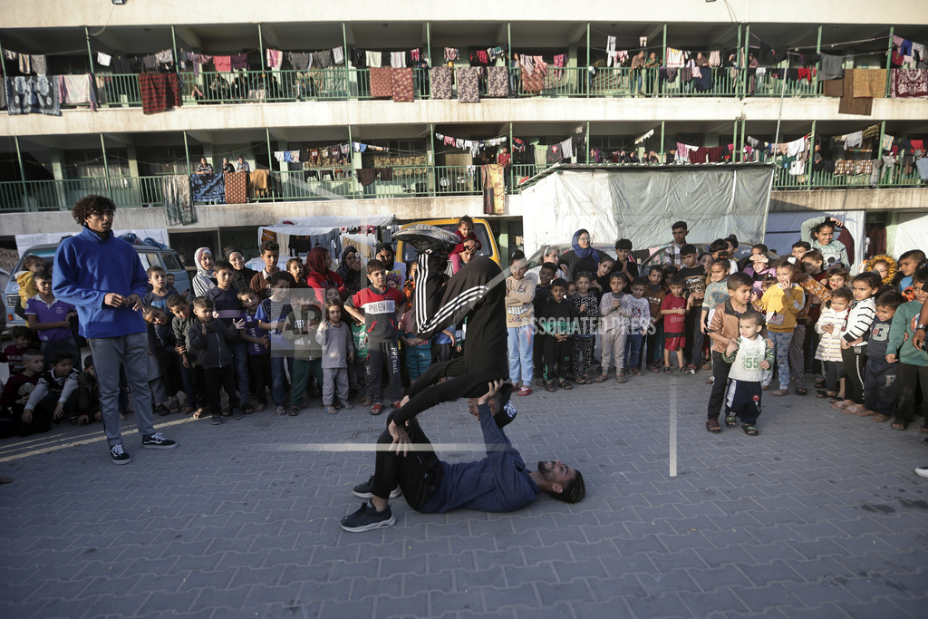 Palestinians present an entertainment performance for displaced children sheltering at a UN school