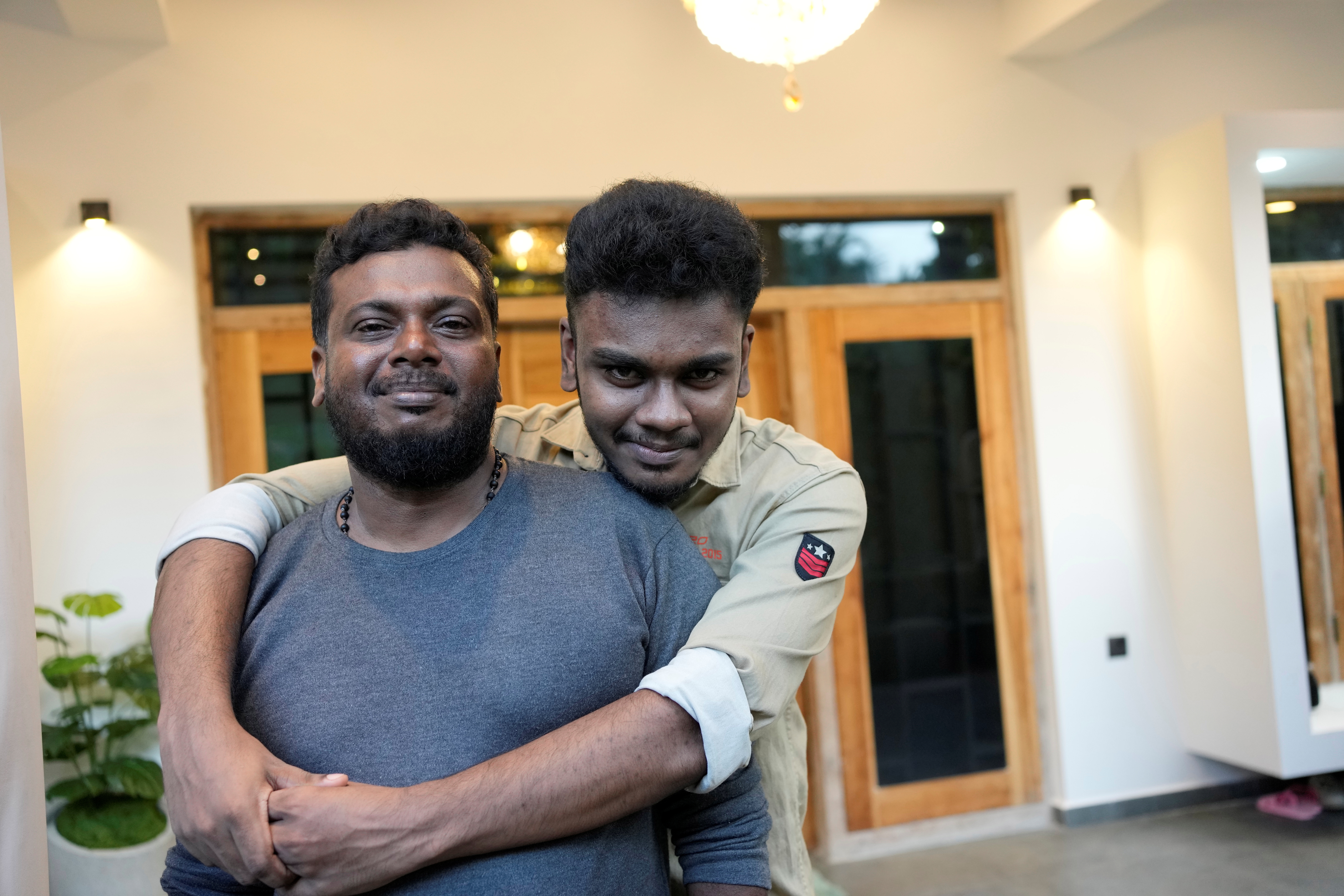 Jayarasa Abilash, right, known as Baby 81 after he was swept away by the 2004 Indian ocean tsunami, shares a light moment with his father Murugupillai at his residence in Kurukkalmadam, Sri Lanka, Tuesday, Dec. 17, 2024.