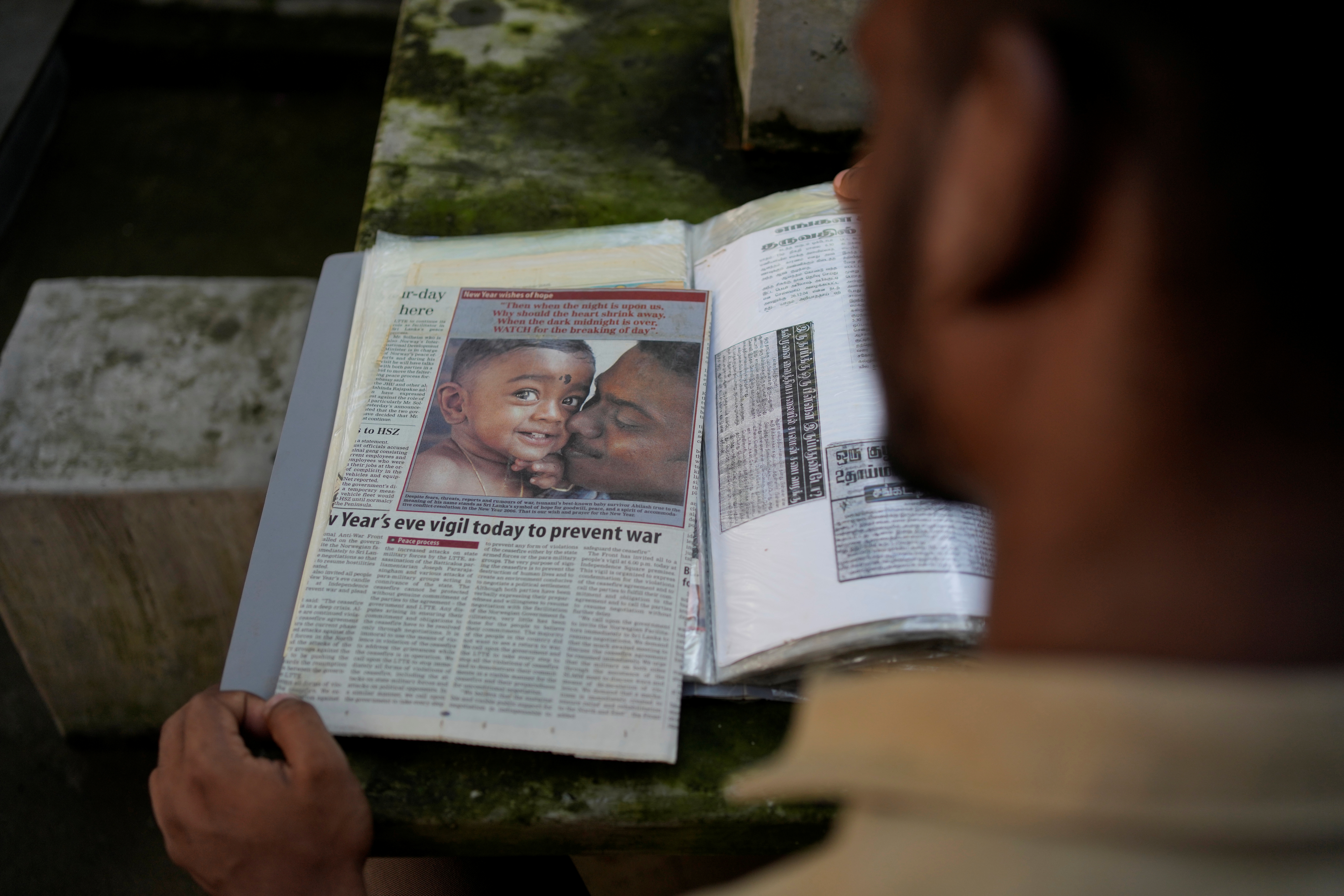 Jayarasa Abilash, known as Baby 81 after he was swept away by the 2004 Indian ocean tsunami, goes through his photo album at his residence in Kurukkalmadam, Sri Lanka, Tuesday, Dec. 17, 2024.