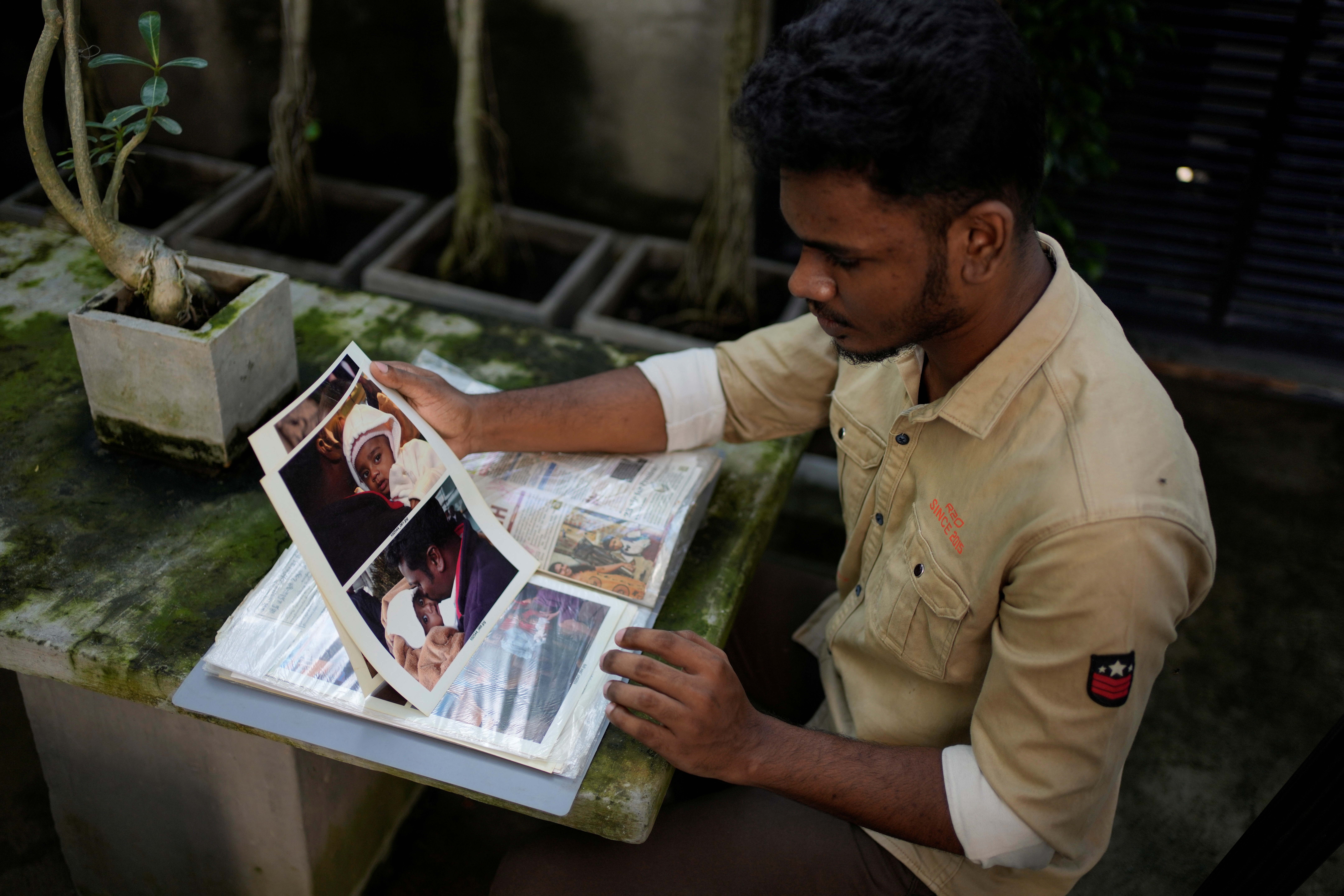 Jayarasa Abilash, known as Baby 81 after he was swept away by the 2004 Indian ocean tsunami goes through his photo album at his residence in Kurukkalmadam, Sri Lanka, Tuesday, Dec. 17, 2024.