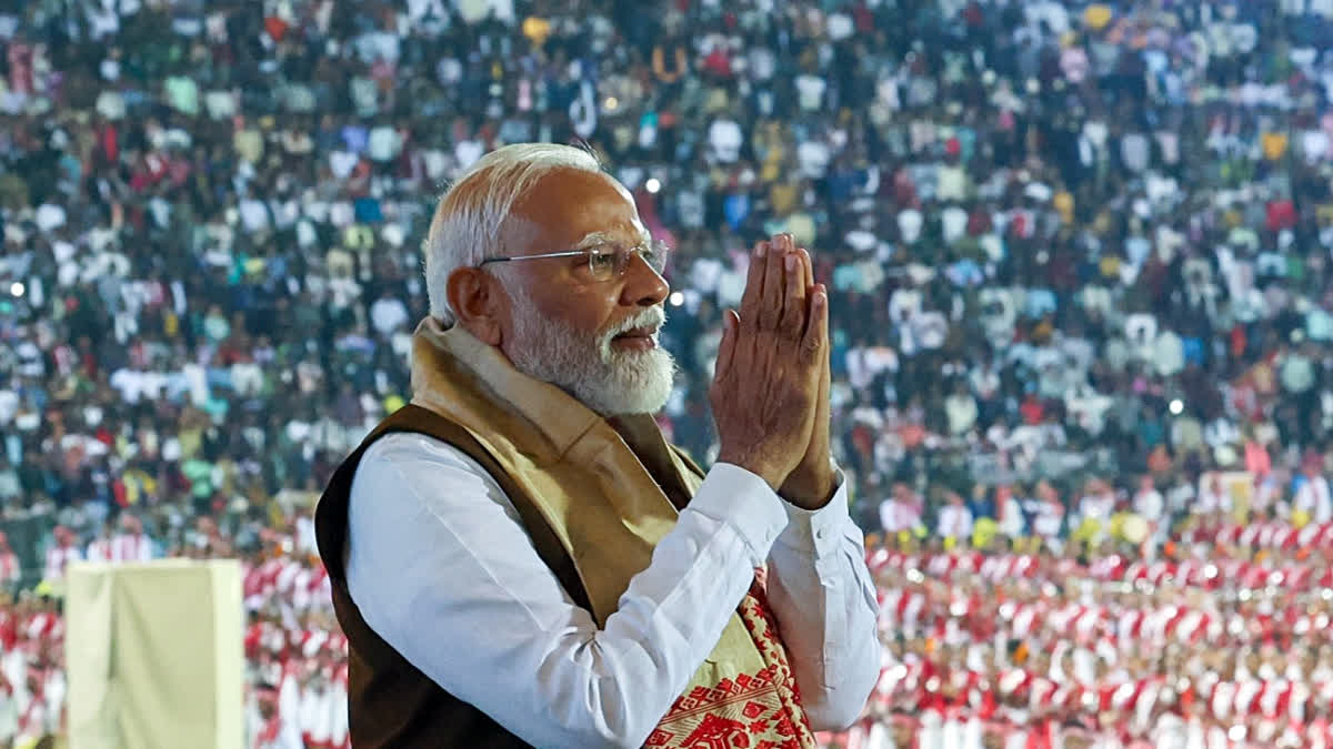 Prime Minister Narendra Modi greets the gathering at the 'Jhumoir Binandini' event, at Sarusajai Stadium in Guwahati.