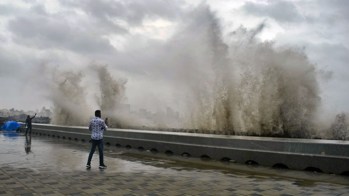 People take pictures of the high tides lashing at the Marine drive following incessant rains, in Mumbai on Wednesday.