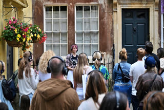 Visitors listen to tour guide Ruby Maidment during a visit to discover the sets of the Netflix series "Bridgerton", in Bath, western England, on July 16, 2024.