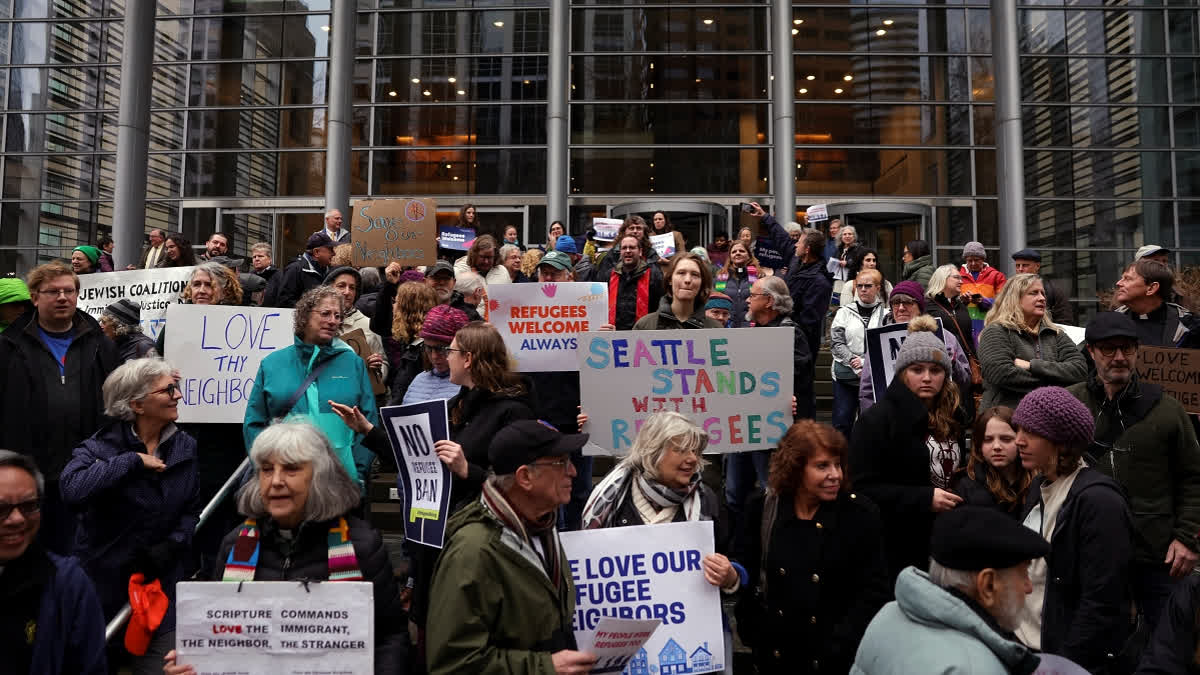 People hold signs as they gather outside the U.S. District Court after a federal judge blocked President Donald Trump's effort to halt the nation's refugee admissions system Tuesday, Feb. 25, 2025, in Seattle.