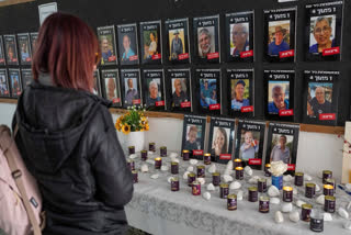 A woman looks at photos of slain hostages (bottom row, L-R) Ariel Bibas, his mother Shiri, his brother, Kfir and Oded Lifshitz, right, that are displayed in the dining hall at Kibbutz Nir Oz, in southern Israel, on Tuesday, Feb. 25, 2025.