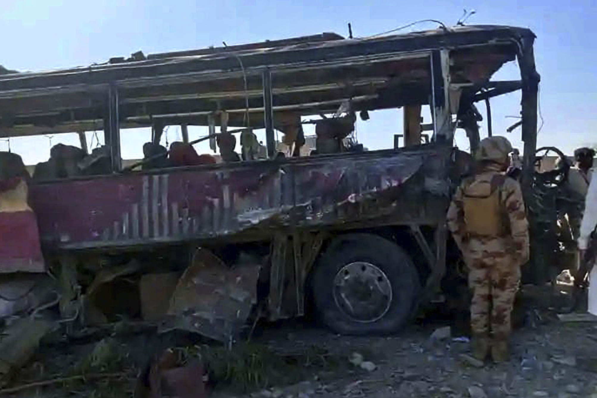 A paramilitary soldier examines a damaged bus at the site of a suicide bombing, in Naushki