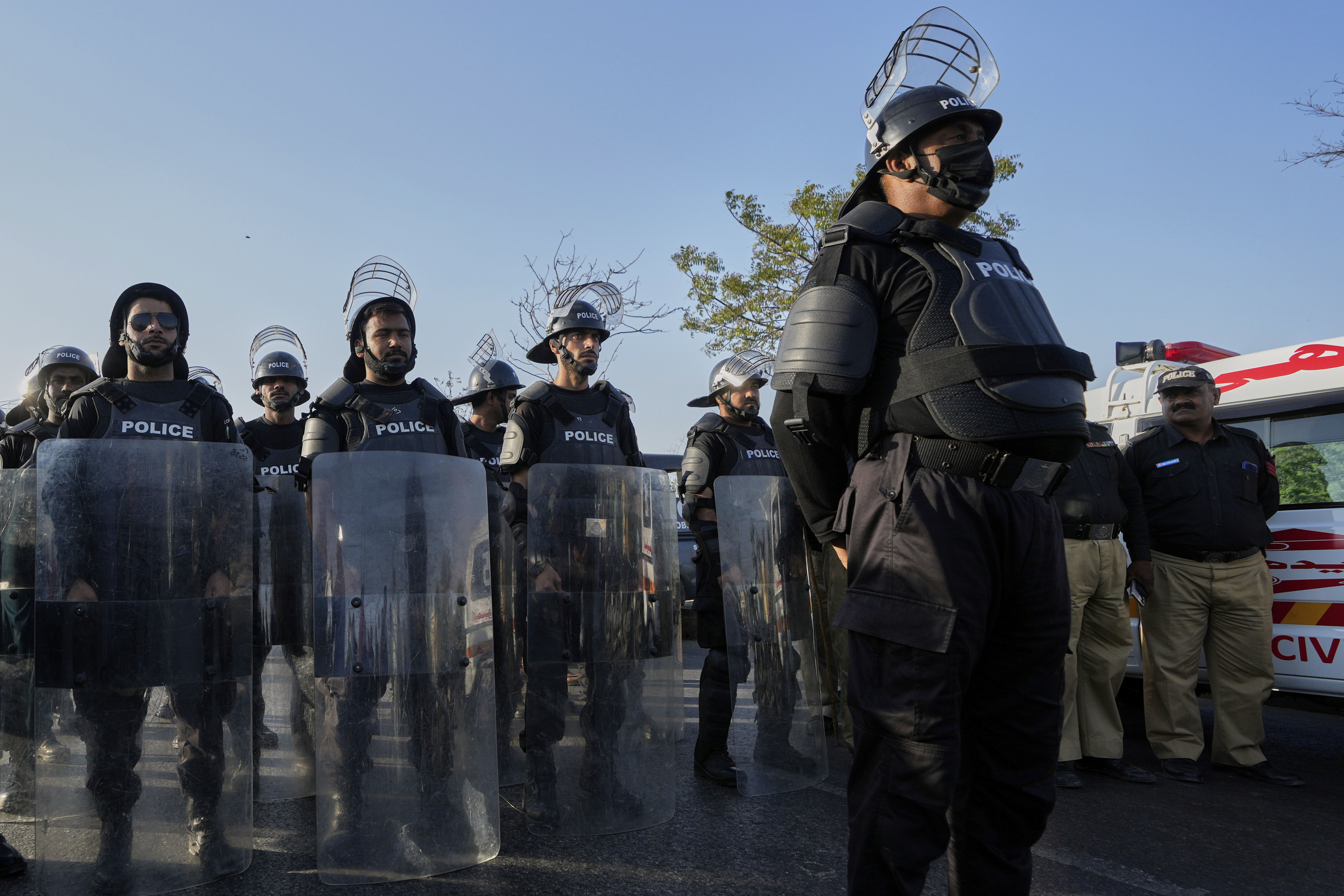 Police officers stand guard with roots gears at a road rally, in Karachi