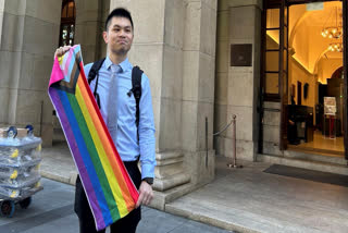 Nick Infinger, who won a years-long legal battle over the differential treatment facing same-sex couples, holds up a rainbow banner after speaking to media members outside Hong Kong’s top court on Tuesday, Nov. 26, 2024.