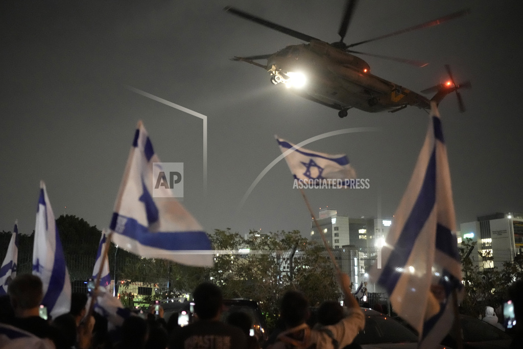 A group of Israelis watch as a helicopter carrying hostages released from the Gaza Strip