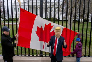 FILE - Toronto residents Douglas Bloomfield, left, and his son Phoenix, right, hold a Canadian flag and an ice hockey stick to show their support for Canada regarding trade tariffs as they pose with with another visitor to the city wearing a mask of President Donald Trump in front of the White House in Washington, March 13, 2025.
