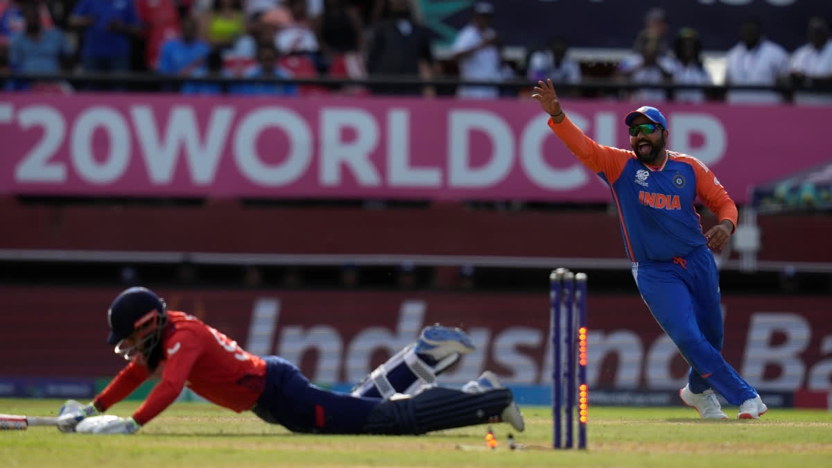 India's captain Rohit Sharma, right, celebrates the run-out of England's Adil Rashid, on ground, during the ICC Men's T20 World Cup second semifinal cricket match between England a