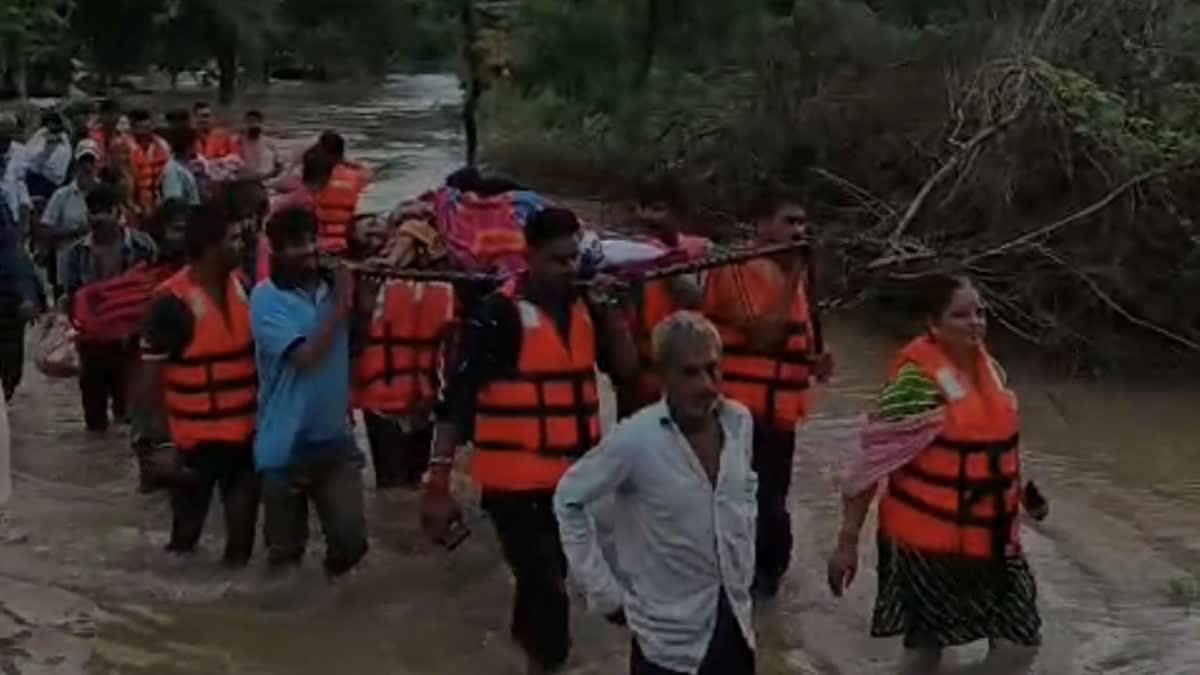 મહિલાને વરસાદી પાણીમાંથી લઈ જવાઈ