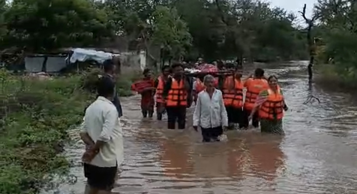 મહિલાને વરસાદી પાણીમાંથી લઈ જવાઈ