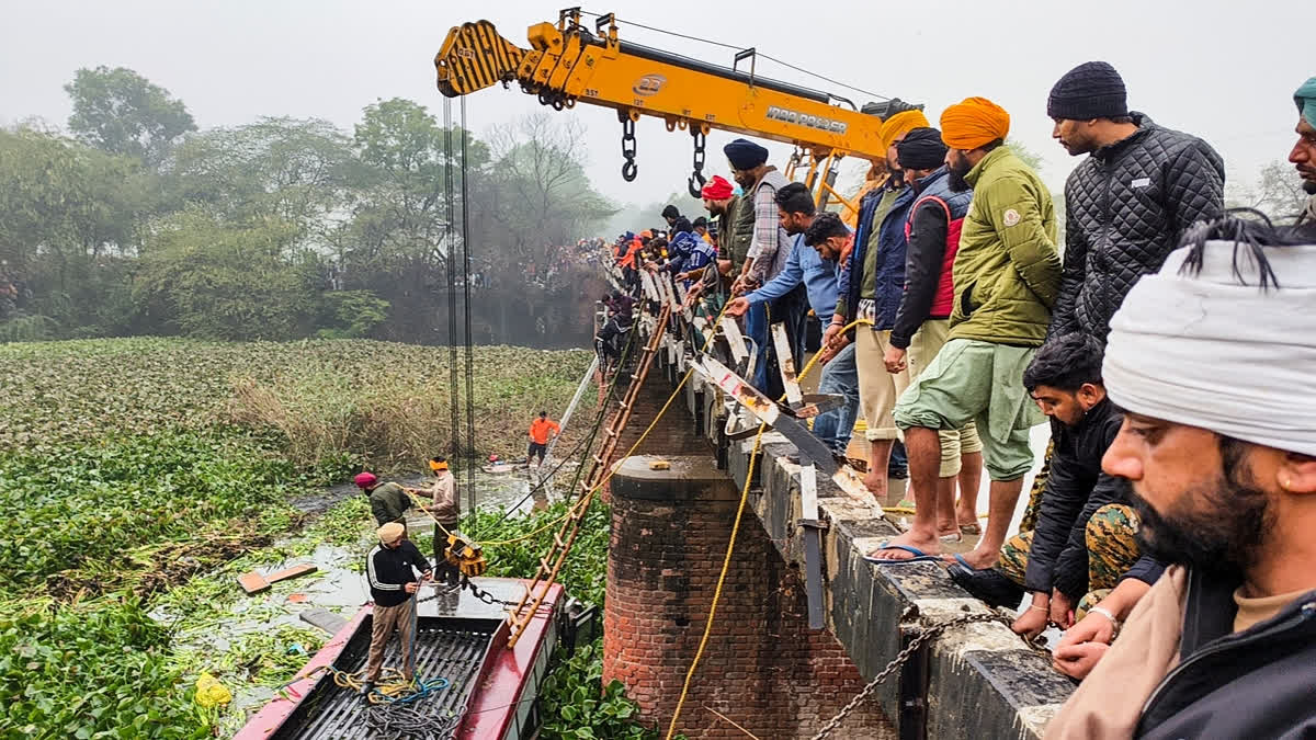 A crane pulls the wreckage of a bus that fell into a nullah after an accident, in Bathinda, Friday, Dec. 27, 2024.