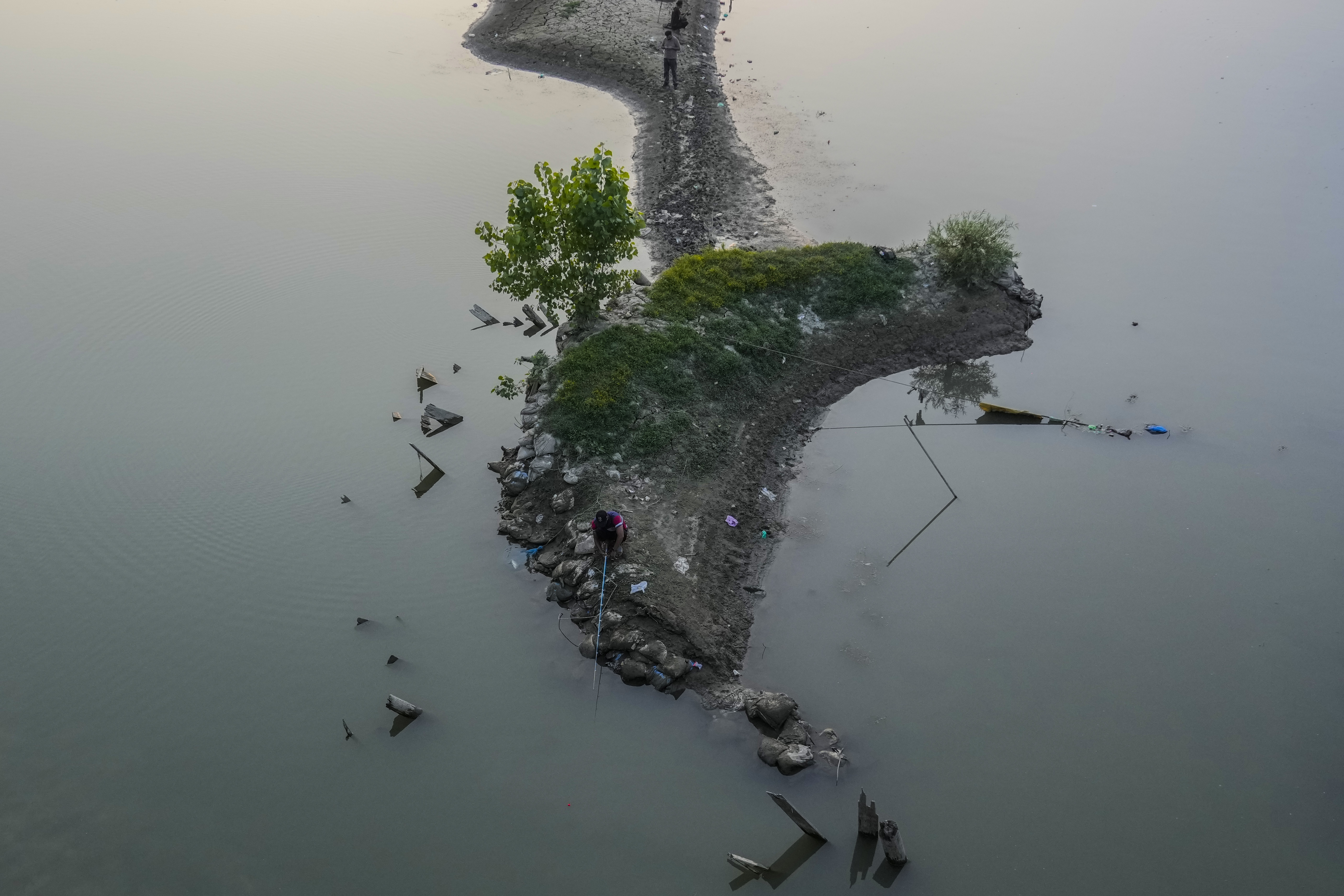 Kashmiris fish in the dried portion of the Jhelum river on a hot summer day in Srinagar on July 25, 2024.