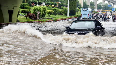 A vehicles wades through a severely waterlogged road after heavy rain lash, at Dhaula Kuan in New Delhi.