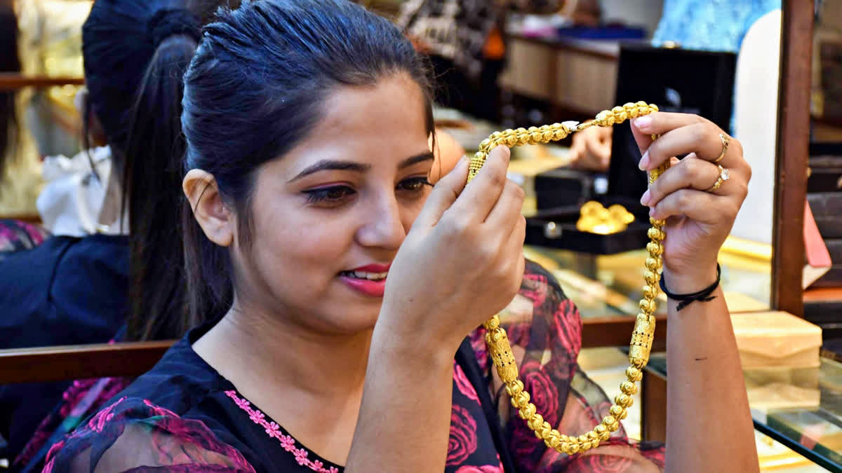 A woman shops for gold jewelry at a showroom ahead of the Dhanteras festival, in Guwahati on Oct 26, 2024.