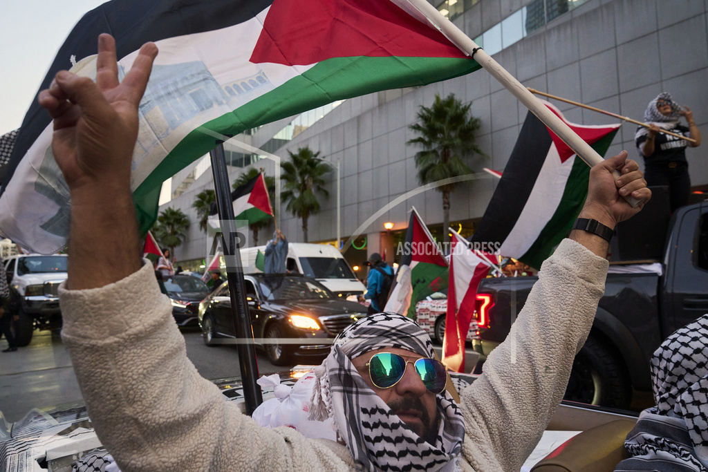 Demonstrators wave Palestinian flags from atop cars during a rally in downtown Los Angeles