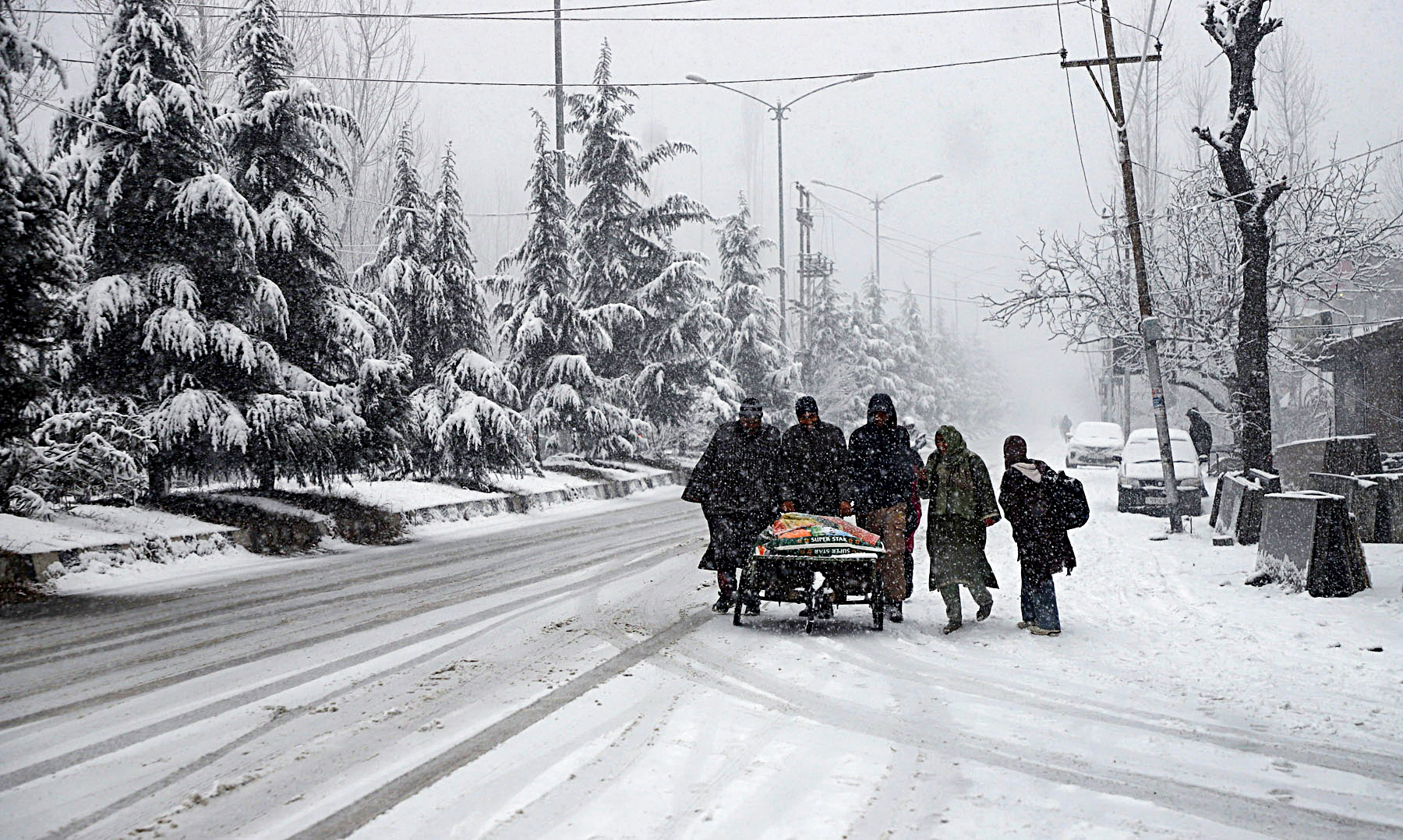 People walk on a snow-covered path amid snowfall, on Saturday.