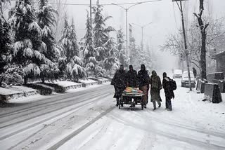 People walk on a snow-covered path amid snowfall, on Saturday.