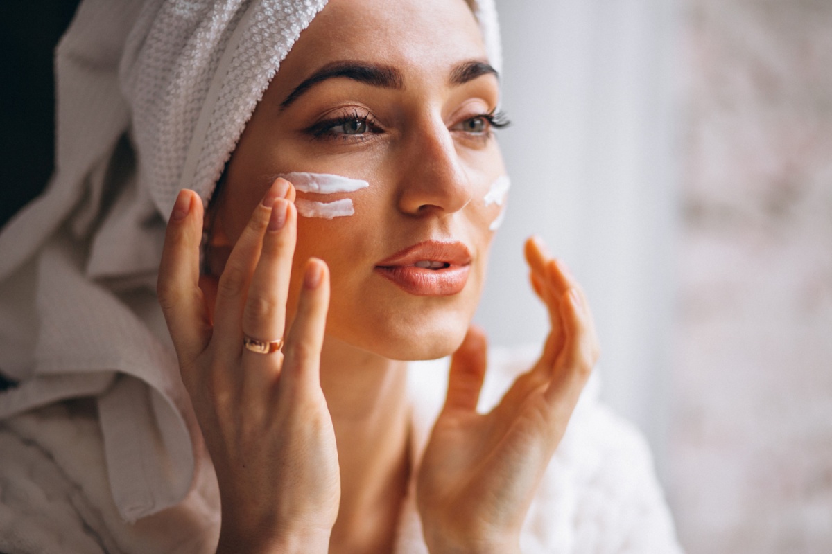 Woman applying cream to her face