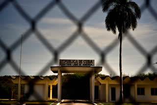 FILE - In this photo reviewed by U.S. military officials, a building in Cuba carries the Spanish message "Republic of Cuba. Free American Territory," behind a gate marking the border with the U.S. Guantanamo Bay naval base in Cuba, June 6, 2018.