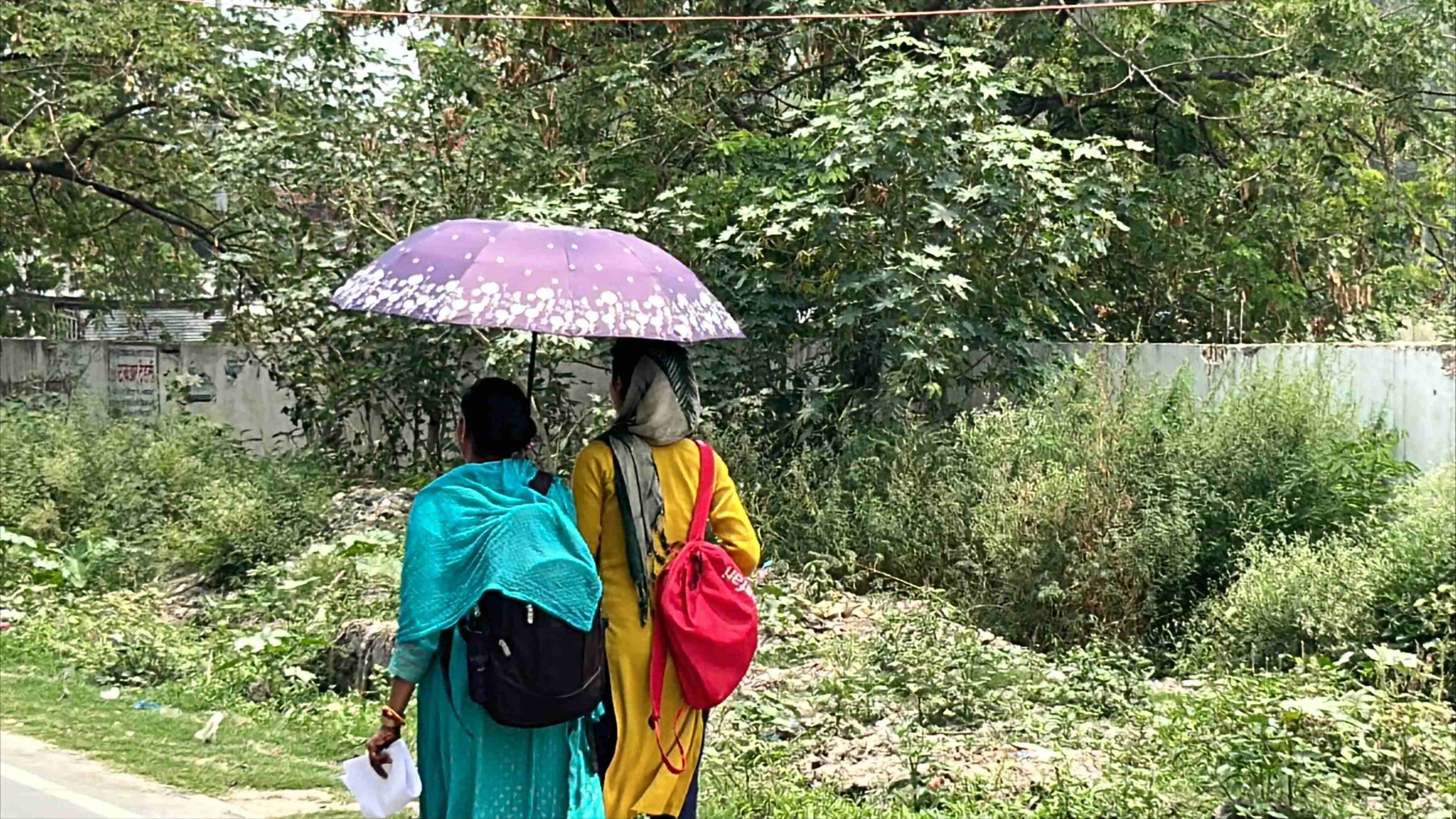 गर्मी से बचने के लिए छाता का इस्तेमाल करतीं छात्राएं.