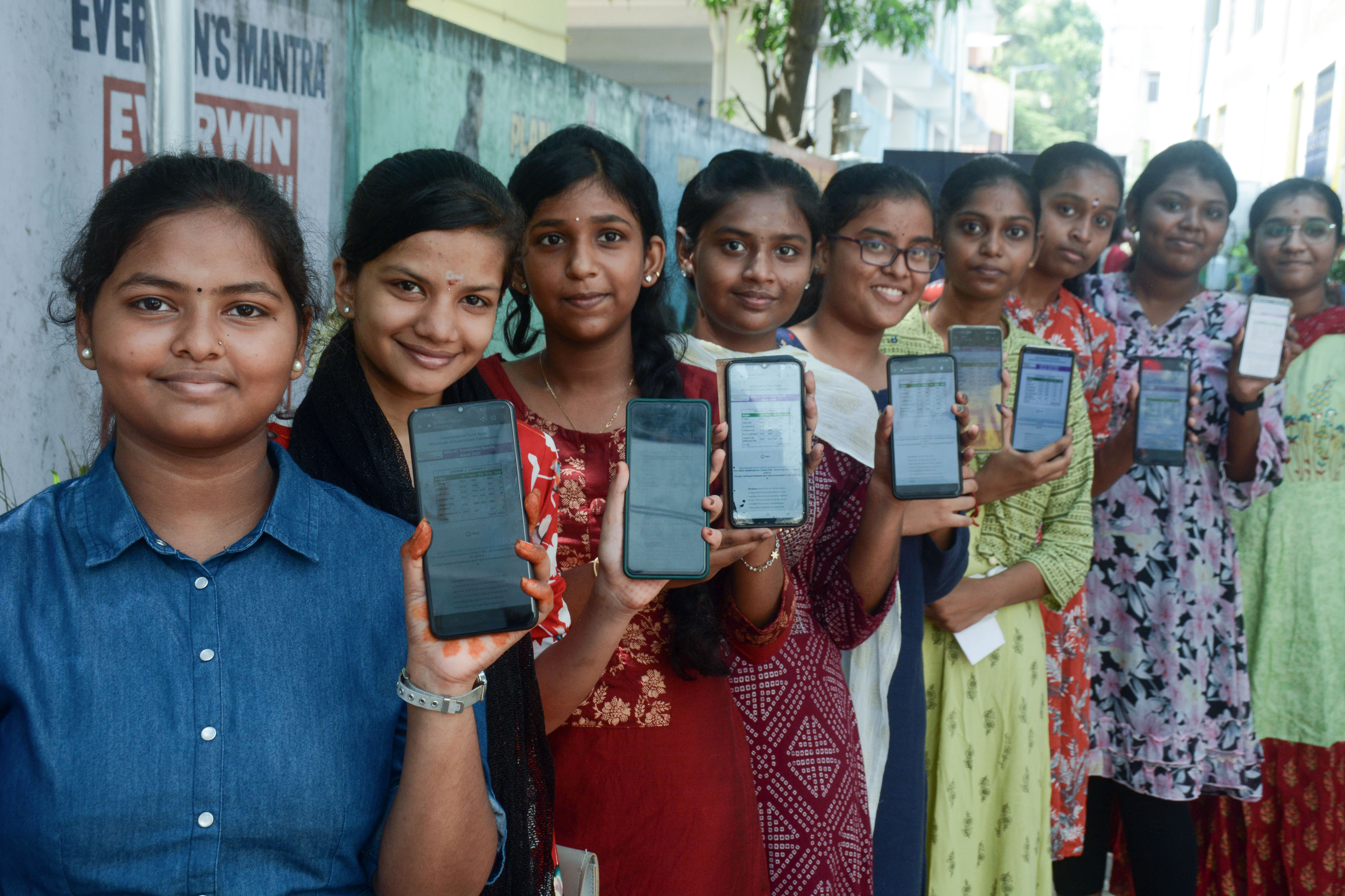 Students show their class 12 marks on mobile phones.