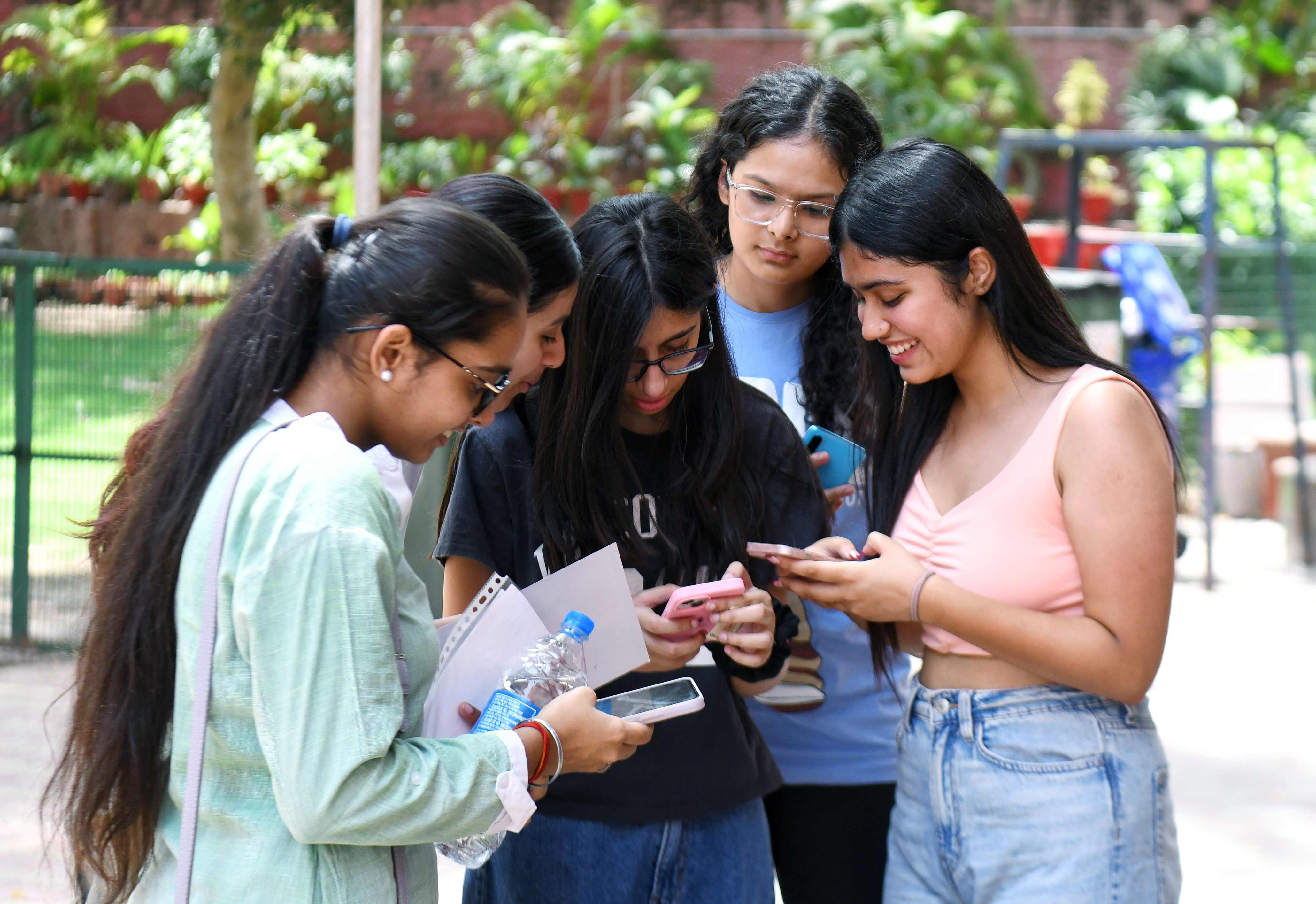 Students check their CBSE 12th board results on their mobile phones at St. Thomas School, in New Delhi on Tuesday.