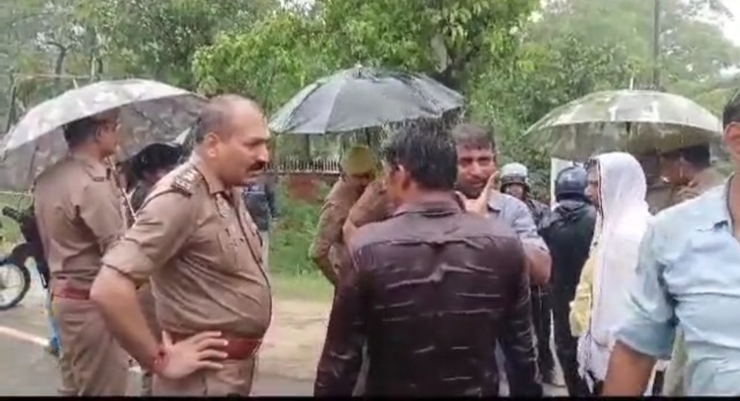 बारिश में प्रदर्शन कर रहे ग्रामीणों से बात करती पुलिस टीम