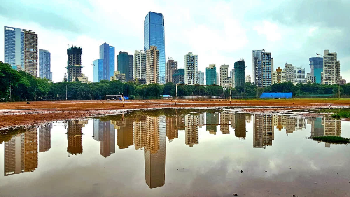 A reflection of the tall buildings of Shivaji Park seen in a puddle of water after rainfall, in Mumbai on June 7, 2024.
