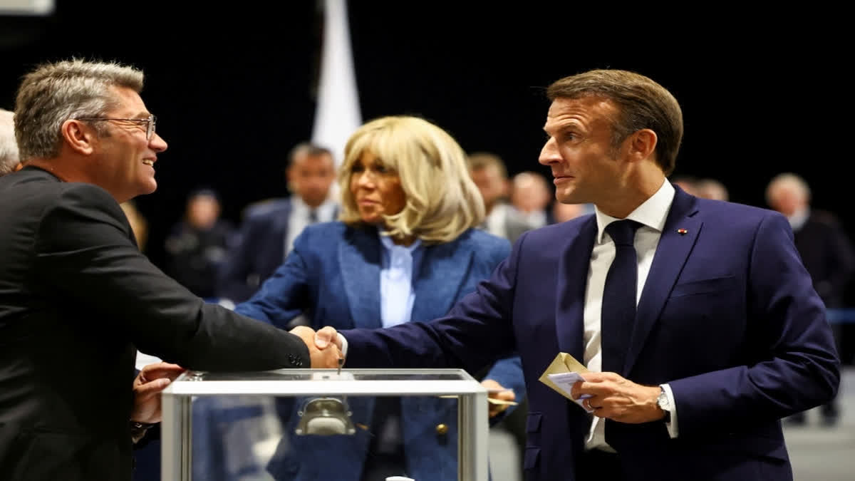 French President Emmanuel Macron shakes hands with a polling station official during the EU election