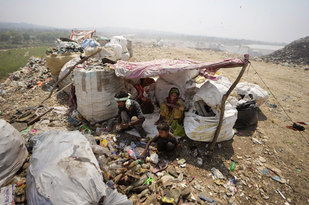 Waste pickers Arjun, 6, sorts recyclable items with his parents at a garbage dump site during a heat wave on the outskirts of Jammu, June 19, 2024.